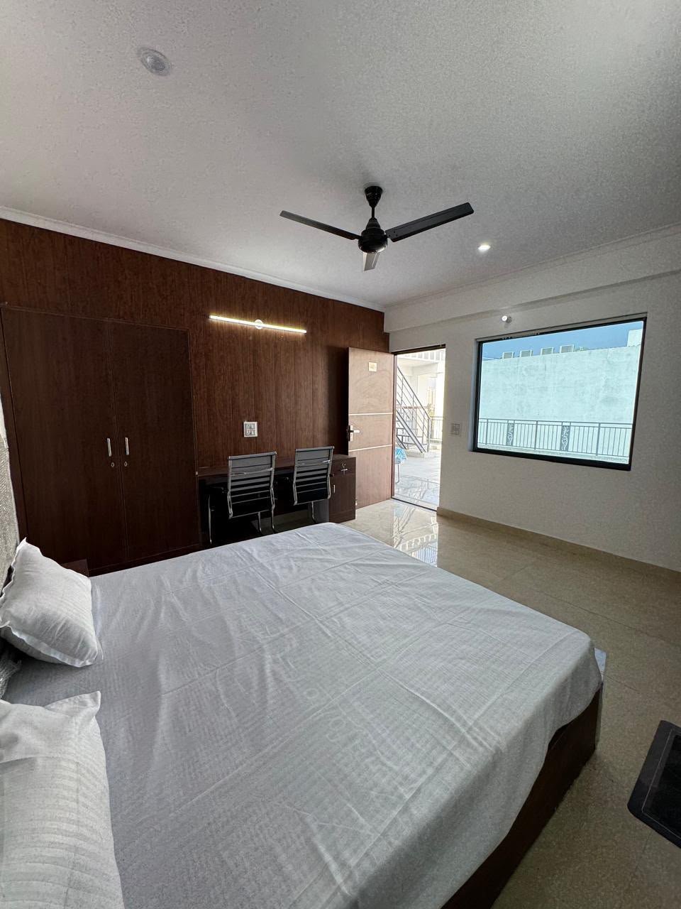 Spacious sunlit bedroom interior with large window in Noida luxury PG room